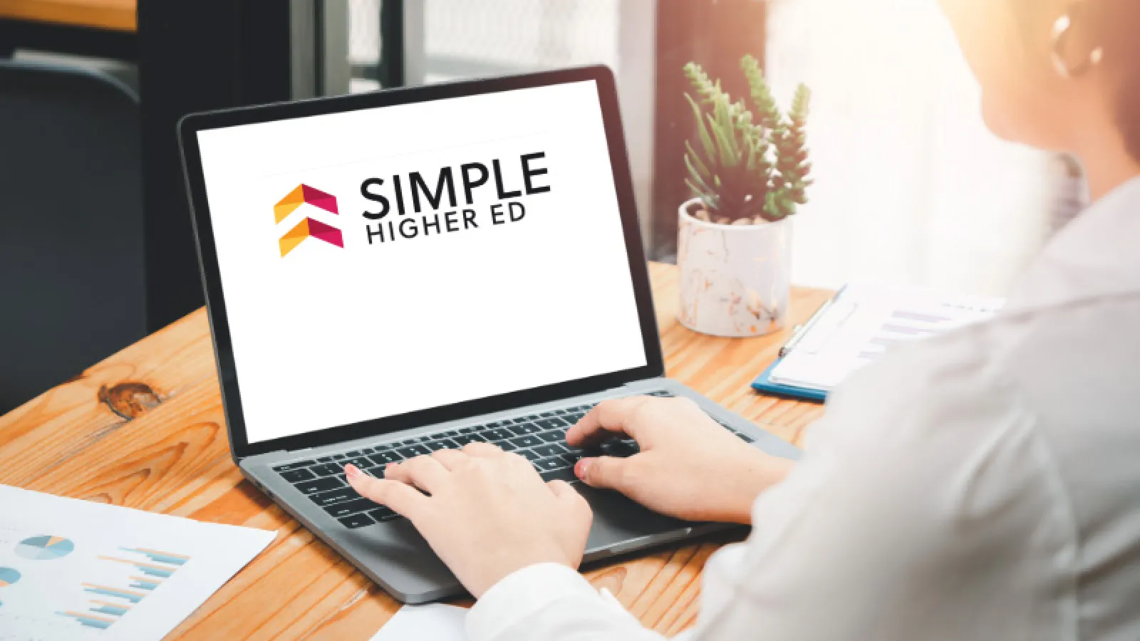 Woman using a laptop with the words Simple Higher Ed on the screen